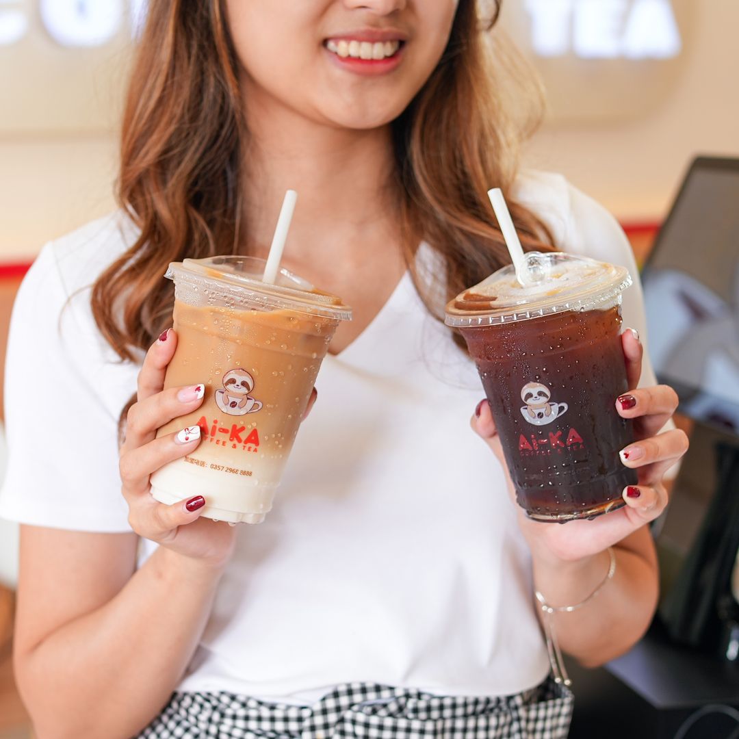 seorang wanita sedang bahagia sambil memegang dua gelas kopi Ai-KA