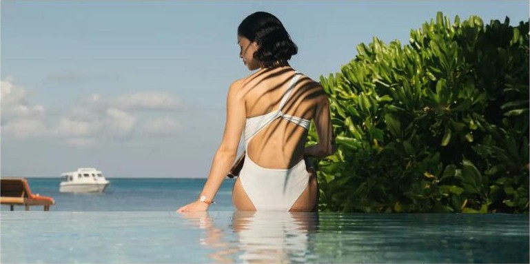 ผู้หญิงนั่งริมสระว่ายน้ำมองทะเลที่ Club Med Kani