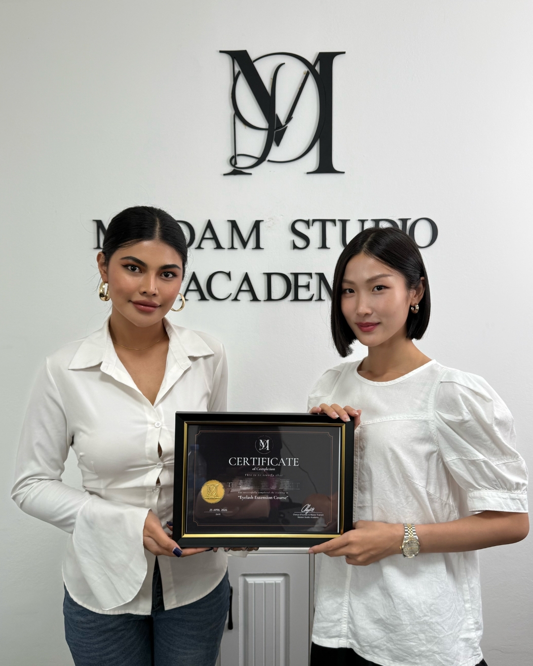 Graduate receiving an eyelash extension course certificate at Madam Studio Academy.