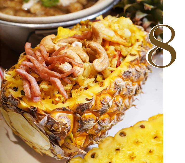 A beautifully presented Pineapple Fried Rice with shrimp, chicken, ham, and cashew nuts, served inside a fresh hollowed-out pineapple shell at Hua Seng Hong restaurant.