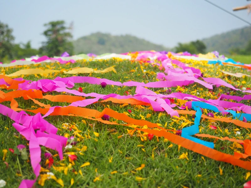 ภาพบรรยากาศการตกแต่งสุสานในวันเช็งเม้งด้วยกระดาษสายรุ้งสีสันสดใสบนเนินหญ้า เพื่อแสดงความกตัญญูและรำลึกถึงบรรพบุรุษ
