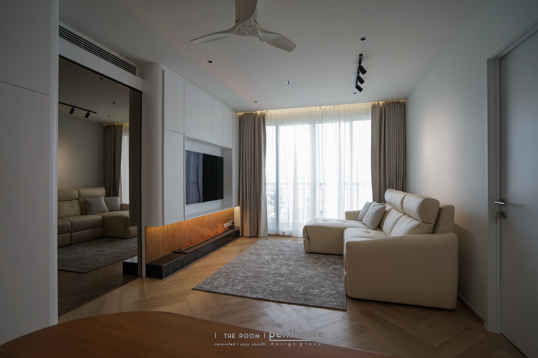 Original project photograph of The Room Sathorn showing built-in storage around the television and a light-coloured sofa