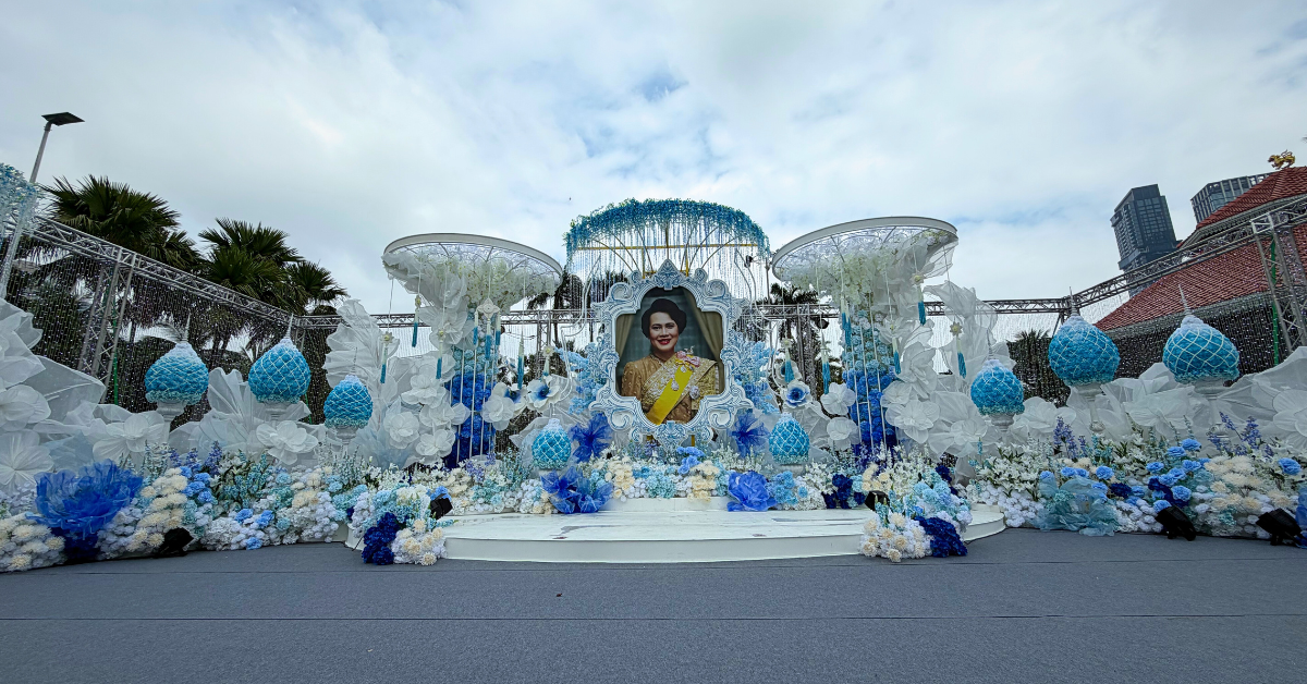 การออกแบบเวทีพิธีการงานกาชาดประจำปี 2568 ใช้องค์ประกอบดอกไม้และโครงสร้างสีฟ้า–ขาว สื่อถึงความสุภาพและเป็นทางการ