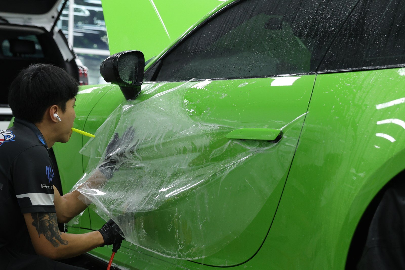 ช่างรีดฟิล์มบริเวณด้านหน้ารถ Porsche สีเขียว