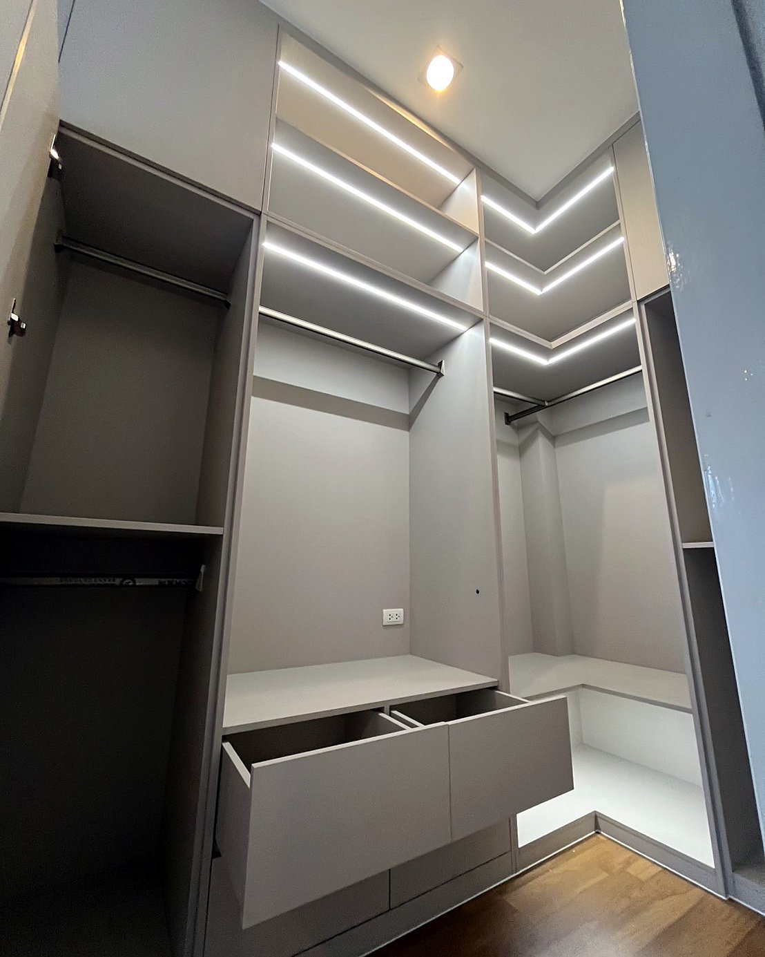 Built-in walk-in wardrobe with hanging rails, shelves, drawers and LED lighting by fync