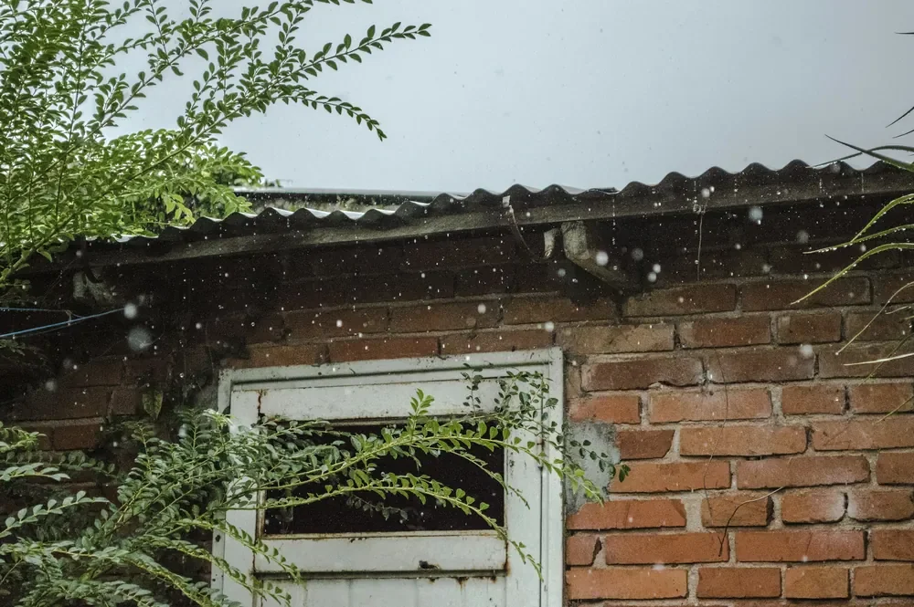 ฝนตกบนหลังคาและผนังอิฐของบ้าน