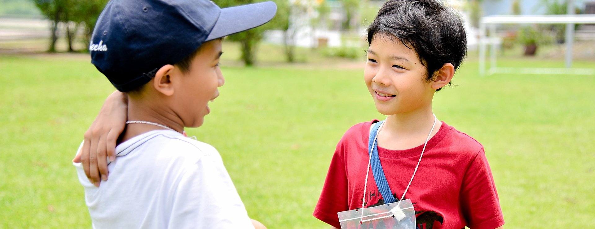 Two children smiling together in a green outdoor setting