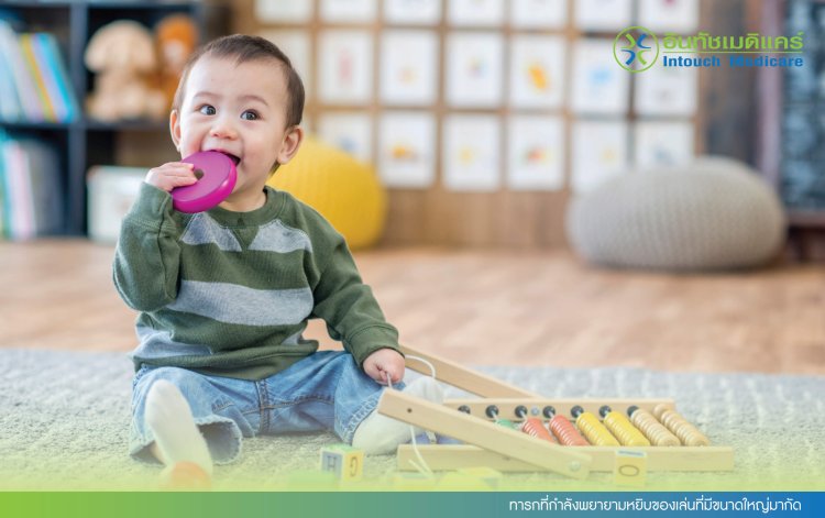 ทารกที่กำลังพยายามหยิบของเล่นที่มีขนาดใหญ่มากัด