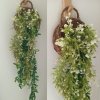 ดอกไม้เลื้อยปลอมสีขาวในตะกร้าสานแขวนผนัง Artificial white climbing flowers in a woven basket.