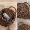 ตะกร้าสานแขวนผนังต้นไม้ปลอมใส่ของใช้ของตกแต่ง Woven wall-mounted basket for holding decorative items and supplies.