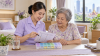 ผู้ดูแลทบทวนรายการยาและกล่องจัดยากับผู้สูงอายุ | Caregiver reviewing a medication list and pill organiser with an older adult ผู้ดูแลทบทวนรายการยาและกล่องจัดยากับผู้สูงอายุ | Caregiver reviewing a medication list and pill organiser with an older adult