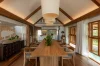 The living and dining pavilion from the far end, woven lanterns hanging from the timber roof