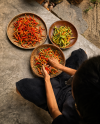 Red and yellow chillies laid out to dry in round woven trays, sorted by hand