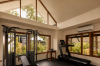 The gym beneath its vaulted ceiling, with cable machine and treadmill facing the garden