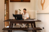A guest working at the timber desk beneath the woven wall piece