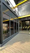 Paved walkway beside glass doors beneath an upper-floor balcony