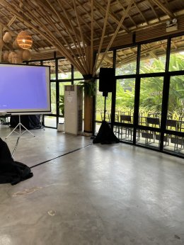 ลำโพงบนขาตั้งด้านขวาของจอโปรเจคเตอร์ภายในสถานที่จัดงาน