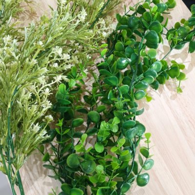 ดอกไม้เลื้อยปลอมสีขาวในตะกร้าสานแขวนผนัง Artificial white climbing flowers in a woven basket.
