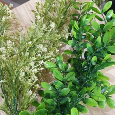 ดอกไม้เลื้อยปลอมสีขาวในตะกร้าสานแขวนผนัง Artificial white climbing flowers in a woven basket.