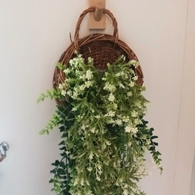 ดอกไม้เลื้อยปลอมสีขาวในตะกร้าสานแขวนผนัง Artificial white climbing flowers in a woven basket.