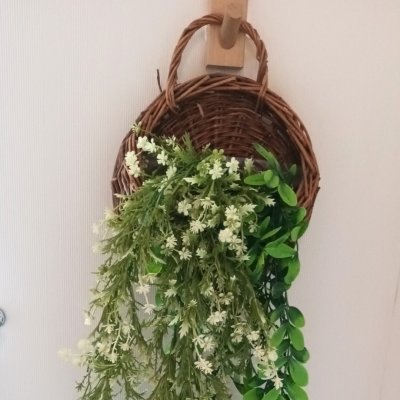 ดอกไม้เลื้อยปลอมสีขาวในตะกร้าสานแขวนผนัง Artificial white climbing flowers in a woven basket.