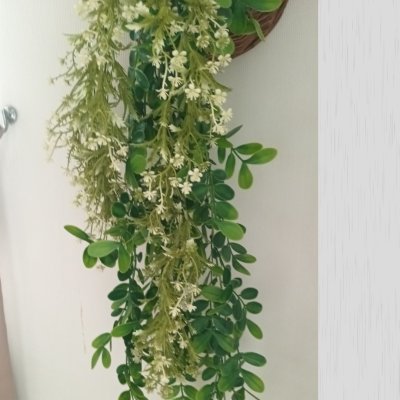 ดอกไม้เลื้อยปลอมสีขาวในตะกร้าสานแขวนผนัง Artificial white climbing flowers in a woven basket.