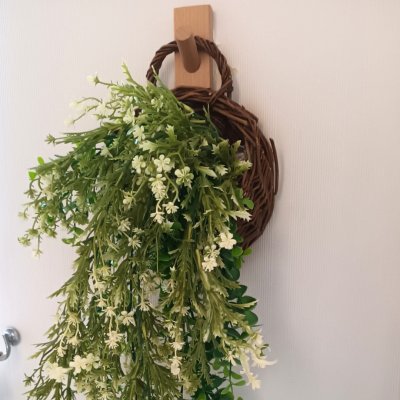 ดอกไม้เลื้อยปลอมสีขาวในตะกร้าสานแขวนผนัง Artificial white climbing flowers in a woven basket.