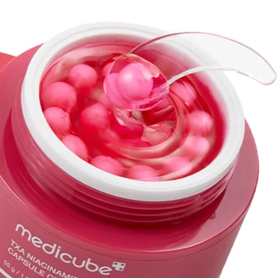 ไม้พาย (Spatula) ตักเนื้อครีมแคปซูล Medicube TXA Niacinamide ที่แสดงการแยกกันของแคปซูลสีชมพูและเจลสีแดง