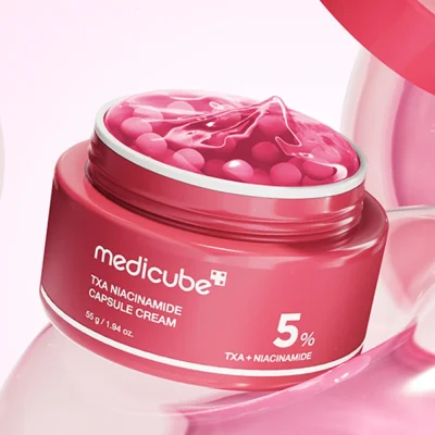 กระปุก Medicube TXA Niacinamide Capsule Cream เปิดฝาให้เห็นเนื้อเจลสีแดงและแคปซูลสีชมพูที่ช่วยลดฝ้า กระ