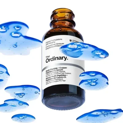 ขวดผลิตภัณฑ์เซรั่ม The Ordinary Multi-Peptide + Copper Peptides 1% Serum ท่ามกลางเนื้อเซรั่มสีฟ้า