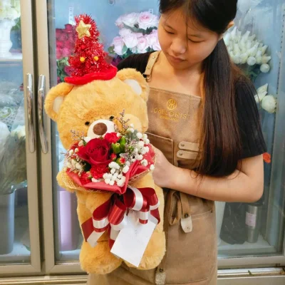 หมีสีน้ำตาลหมวกแดงอุ้มดอกไม้