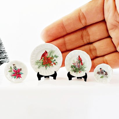 Miniature Christmas plates with cardinal designs, perfect for dollhouse holiday decor and adding festive cheer to miniature scenes.