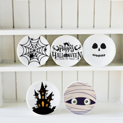 Tiny Halloween-themed plates for dollhouse decor, featuring eerie designs such as a skull, haunted house, and creepy mummy face.