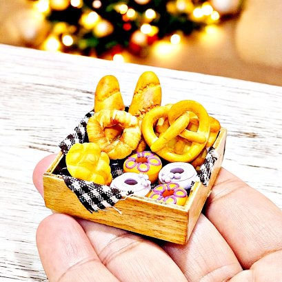 Miniature bread and donuts set in a wooden crate for dollhouse bakery or kitchen display.