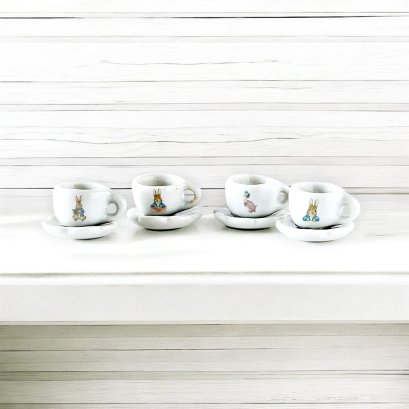 Set of four miniature espresso cups with Peter Rabbit designs, featuring matching saucers, perfect for dollhouse decor and 1:12 scale collections