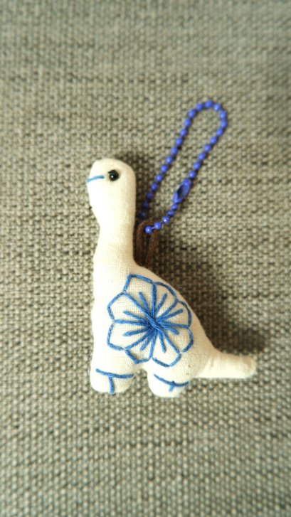 White dinosaur keychain, purple cord