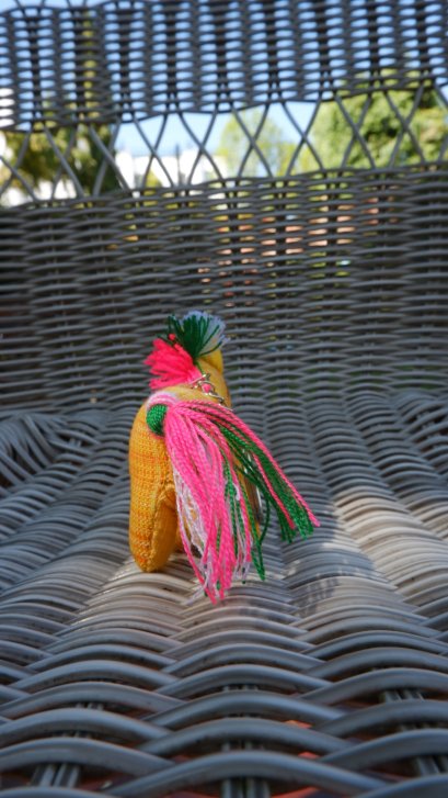 Yellow horse keychain with white, pink, green tail