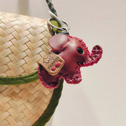 Red baby elephant keychain with a brown saddle