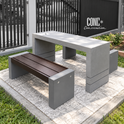 ชุดโต๊ะสนามไฟเบอร์ท็อปทูโทน CONC Concreation โต๊ะไฟเบอร์สีเทาปูน พร้อมม้านั่ง CONWOOD สีไม้โอ๊คเข้ม ฐานปูนซีเมนต์ 2 ตัว จัดวางในสวนกลางแจ้ง