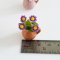 Miniature arrangement of purple daisy flowers in a clay jug, perfect for dollhouse decor and fairy gardens.