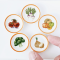 A collection of miniature white plates with vibrant vegetable designs, perfect for dollhouse and fairy garden decor.