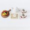 Handcrafted miniature tea set with floral teapot, cups, a fruit tart on a wooden board, and a box of Ferrero Rocher chocolates, perfect for dollhouse decor and collectors.