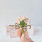 Miniature pink rose bouquet tied with twine and accompanied by a tiny vintage-style gift card, perfect for dollhouse decor or special gifts.