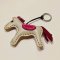 Light gray horse keychain with a dark red tail